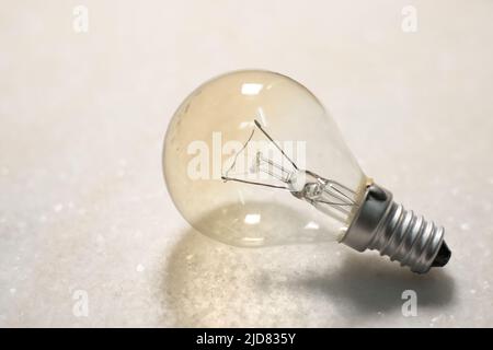 Une petite ampoule à incandescence ou une lampe sur une surface dure blanche Banque D'Images