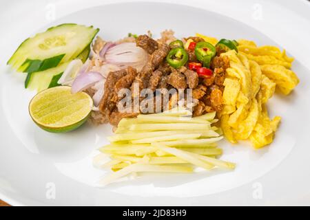 Gros plan sur la pâte de crevettes, riz frit avec du porc doux, un demi-citron, des tranches de concombre, des mangues fraîches, des oignons, des œufs de poulet frits et des fres Banque D'Images