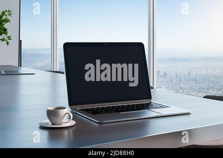 Écran noir vierge pour ordinateur portable avec espace publicitaire pour votre logo sur une table en bois sombre avec une tasse à café dans une pièce ensoleillée et vue sur la ville depuis une grande fenêtre. 3D rendu, Banque D'Images