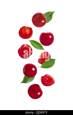 Cerise tombant avec des feuilles vertes isolées sur un fond blanc. Motif baies rouges volantes. Cerises entières et tranchetées. Fruits biologiques. Banque D'Images