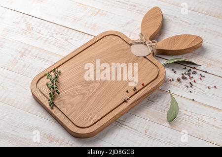 planche à découper carrée en bois avec oreilles de lièvre en forme de poignée et épices sur fond blanc. maquette avec espace pour le texte, vue latérale Banque D'Images