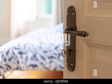 Chambre d'hôtel ou intérieur de chambre de maison élégant. Porte ouverte, bouton de porte rétro et clé sur porte en bois vintage blanc, vue rapprochée. Banque D'Images