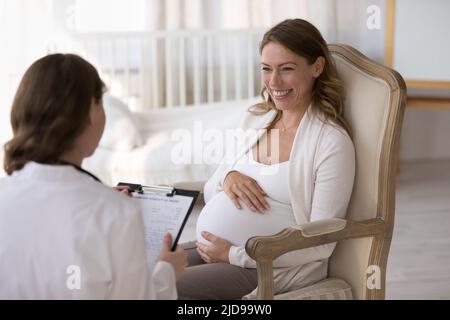 Obstétricien gynécologue remplissant la forme médicale pendant la visite de la femme enceinte Banque D'Images