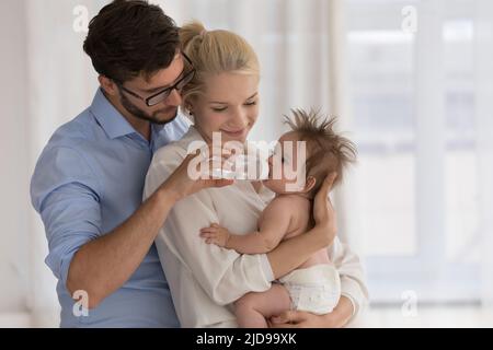 Bébé en couche sur les bras des parents boit de l'eau du biberon Banque D'Images