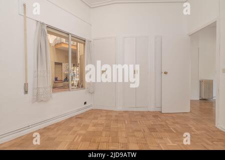 Salon vide avec parquet en chêne et menuiserie blanche, parquet en chêne, armoires à trois corps avec six portes et murs peints en blanc Uni Banque D'Images