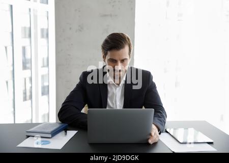 Homme d'affaires du millénaire travaillant sur un ordinateur portable sur un lieu de travail moderne Banque D'Images