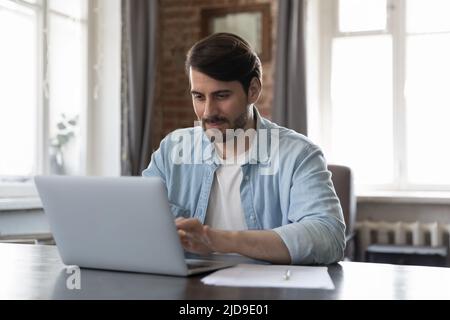 Homme tapant sur le clavier de l'ordinateur portable travaillant assis au bureau Banque D'Images