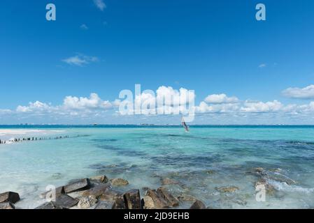 Homme sur une planche à voile près d'une plage à Isla Mujeres, Mexique, contre le ciel bleu pendant les vacances d'été Banque D'Images