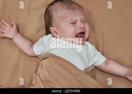 Bébé pleure, enveloppé dans une couverture. Petite petite fille mignonne Banque D'Images