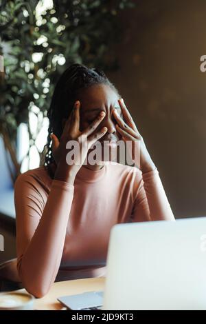 Jeune femme afro-américaine malheureuse avec des dreadlocks pleurant couvrant les yeux avec les mains dans la maison de café de près. Dépression fille noire souffrance, dépairé Banque D'Images