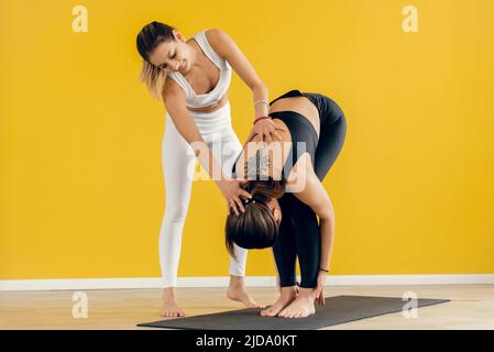 Un instructeur de cours de yoga aide le débutant à faire des exercices d'asana. Bon cours de yoga avec un entraîneur. Exercer le contrôle Banque D'Images