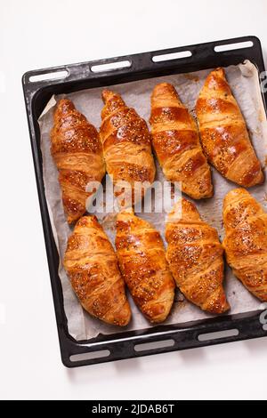 grands croissants dans une plaque de cuisson en métal sur fond blanc, vue de dessus Banque D'Images