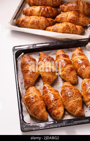 grands croissants dans une plaque de cuisson en métal sur fond blanc, vue de dessus Banque D'Images