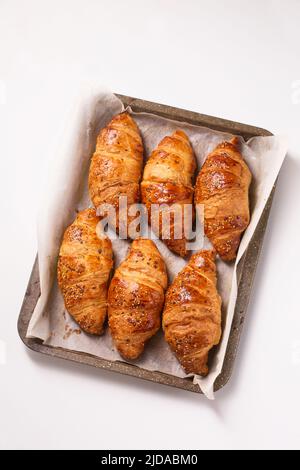 grands croissants dans une plaque de cuisson en métal sur fond blanc, vue de dessus Banque D'Images