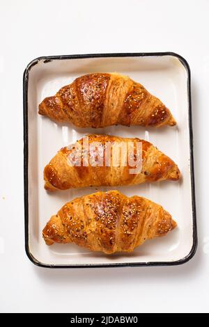 grands croissants dans une plaque de cuisson en métal sur fond blanc, vue de dessus Banque D'Images