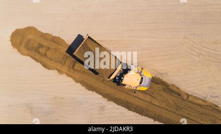 Un camion-benne géant professionnel jaune tirant vers l'arrière avec un tas de sable. Tir de drone. Photo de haute qualité Banque D'Images