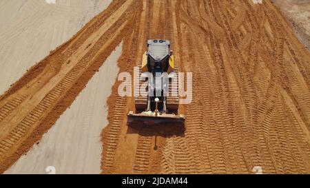 Prise de vue aérienne horizontale en extérieur. Bulldozer pendant les travaux sur un chantier routier laissant des traces dans le sable. . Photo de haute qualité Banque D'Images