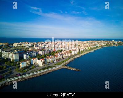 Promenade de la mer avec des personnes marchant près de la mer froide profonde et calme, sur fond de l'ancienne station de la petite ville de Pomorie en Bulgarie sous un ciel nuageux s Banque D'Images