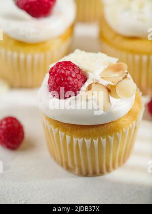 Gros plan. Muffins à la crème, nappés de framboises fraîches et d'amandes. Isolé sur fond blanc. Livre de recettes, restaurant et cuisine maison. Publicité Banque D'Images