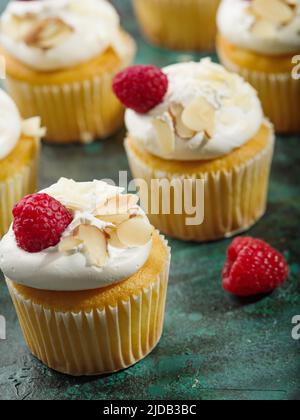 Un cadeau de fête pour un anniversaire, des vacances - des muffins appétissants avec de la crème, des framboises et des amandes sur un fond de marbre vert. Gros plan. T Banque D'Images