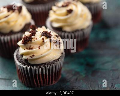 Gros plan. Appétissants muffins au chocolat avec crème au beurre, décorés de copeaux de chocolat sur fond de marbre vert. Il n'y a pas de personnes dans le phot Banque D'Images