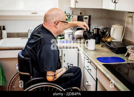 Homme avec des amputations de deux membres versant du café dans la cuisine à la maison; St. Albert, Alberta, Canada Banque D'Images