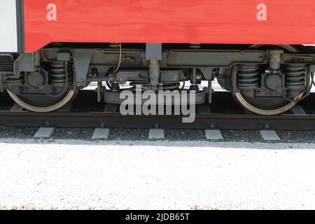 Gros plan des roues d'un essieu d'un wagon de chemin de fer rouge sur des rails Banque D'Images