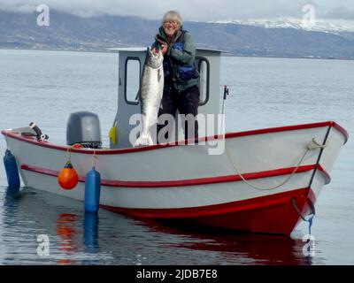 Une résidente de longue date d'Homer montre le saumon roi de 30 livres capturé alors qu'il pêchait à la traîne pour le saumon dans la baie de Kachemak dans son Tolman Skiff fabriqué localement Banque D'Images