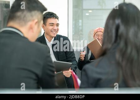 Les employés de bureau rient au milieu d'une réunion. S'amuser à travailler ensemble dans un projet. Banque D'Images