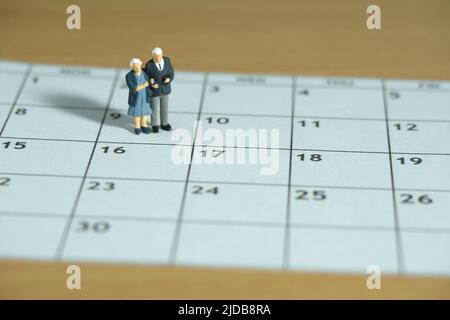 Miniature jouets personnes photographie conceptuelle. Couple de personnes âgées debout au-dessus du calendrier. Concept de datation. Photo d'image Banque D'Images