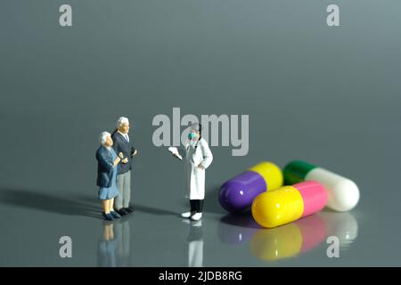 Miniature jouets personnes photographie conceptuelle. Une femme médecin prescrit des médicaments à un couple âgé. Concept de médicaments et de bilan de santé. Image p Banque D'Images
