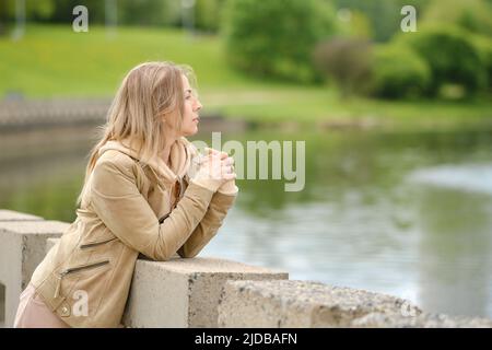 Jolie femme d'âge moyen debout près de la rivière dans le parc de la ville Banque D'Images