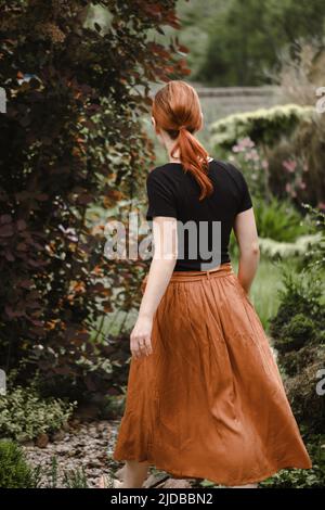 Joyeux cheveux de gingembre femme marchant pieds nus dans le parc ou le jardin. Liberté et mode de vie sain. Femme dans son 40s ayant le repos à l'extérieur. Personnes dans Banque D'Images