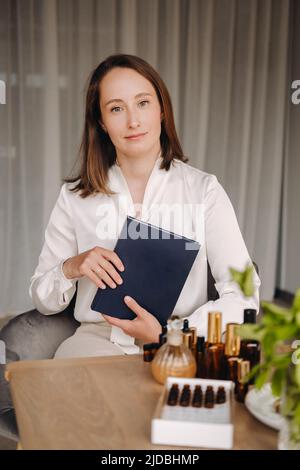 portrait d'une jeune fille souriante assise dans un fauteuil. Un aromathérapeute dans un chemisier blanc est assis dans le bureau. Banque D'Images