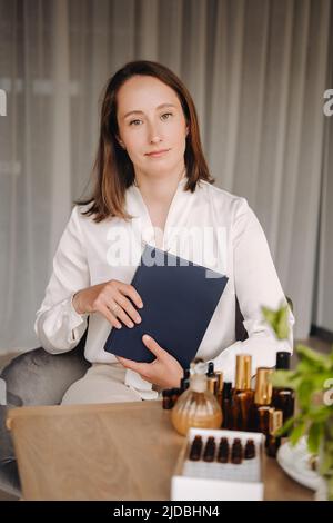 portrait d'une jeune fille souriante assise dans un fauteuil. Un aromathérapeute dans un chemisier blanc est assis dans le bureau. Banque D'Images