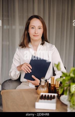 portrait d'une jeune fille souriante assise dans un fauteuil. Un aromathérapeute dans un chemisier blanc est assis dans le bureau. Banque D'Images