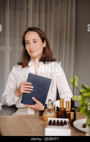 portrait d'une jeune fille souriante assise dans un fauteuil. Un aromathérapeute dans un chemisier blanc est assis dans le bureau. Banque D'Images