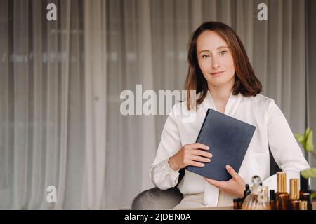 portrait d'une jeune fille souriante assise dans un fauteuil. Un aromathérapeute dans un chemisier blanc est assis dans le bureau. Banque D'Images