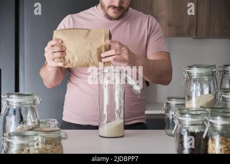 latins méconnaissables remplissant un pot de riz rond provenant d'un sac en papier. Banque D'Images
