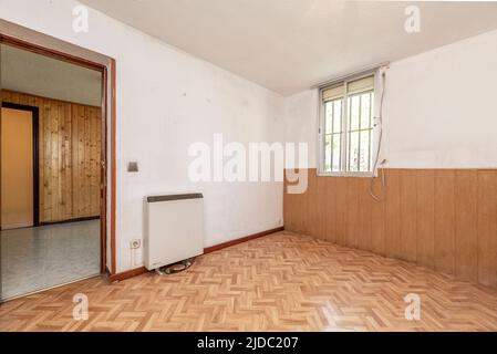 Séjour vide avec murs peints en blanc et PVC et bois de pin à rainure et languette, parquet en chêne et grès blanc en céramique Banque D'Images