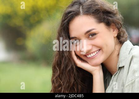 Portrait d'une belle femme qui vous regarde avec un sourire parfait dans un parc Banque D'Images