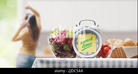 Repas sain à la maison: horloge avec note collante et salade fraîche, femme mince dansant en arrière-plan Banque D'Images