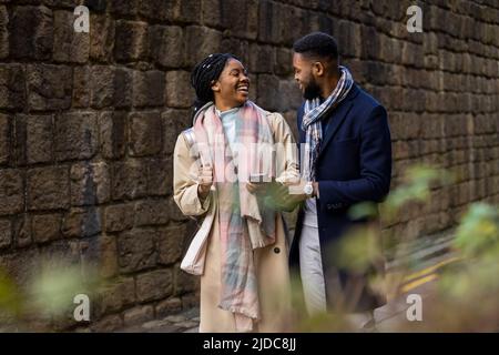 Couple joyeux discutant avec une femme tenant un téléphone portable Banque D'Images