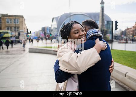 Couple embrassant en ville, femme souriant avec les bras autour de l'homme Banque D'Images