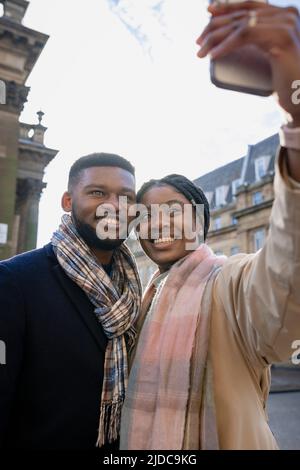 Couple affectueux souriant et prenant un selfie sur un téléphone portable Banque D'Images