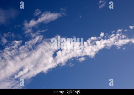 Nuages blancs en diagonale sur le cadre d'un ciel bleu riche. Banque D'Images