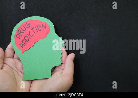 Traitement de la toxicomanie, psychothérapie de réadaptation, et comment traiter le concept. Main tenant le profil de la tête humaine avec le mot de dépendance sur le cerveau. Banque D'Images