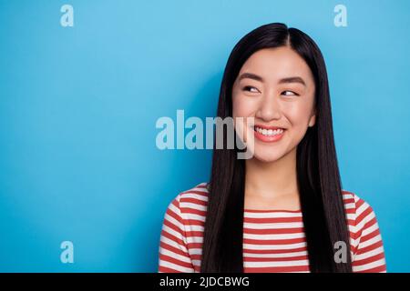 Portrait de charmante fille malaisienne d'esprit sourire tortueuse regarder intéressé vide espace isolé sur fond bleu de couleur Banque D'Images