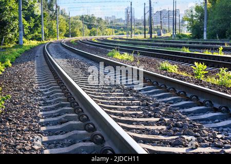 Gros plan sur les voies ferrées d'un chemin de fer à plusieurs voies s'étendant sur la distance avec la toile de fond d'une ville d'été matin à l'horizon. Banque D'Images