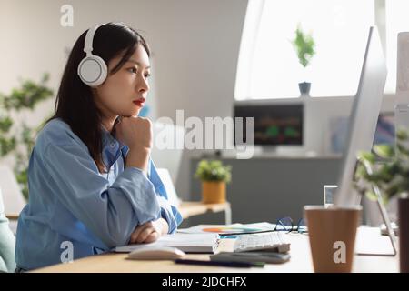 Femme d'affaires asiatique utilisation de l'ordinateur travailler en ligne dans Office, vue latérale Banque D'Images